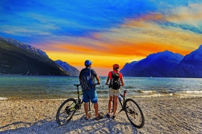 Mountainbiken, Paar mit Fahrrädern bei Sonnenuntergang am Gardasee, Riva